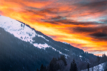 A breathtaking sunset illuminates the snowy mountain peaks, casting a warm glow that contrasts the...
