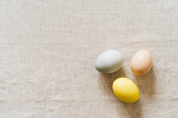 Overhead shot of colourful Easter eggs on linen tablecloth - 748940418