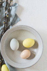 Overhead shot of colourful Easter eggs and twigs on white rustic background - 748940689