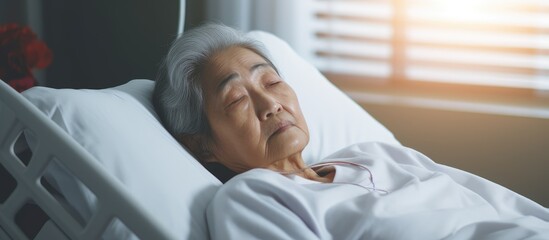 In a hospital ward, an elderly Asian woman is lying in a hospital bed while being cared for by a nurse, physiotherapist, and doctor. They provide support and medical assistance to ensure her health