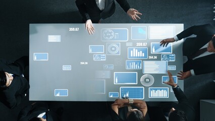 Top down aerial of collaborate professional diverse business people discuss marketing strategy with hologram of marketing data analysis graph, diagram or financial profit investment plan. Directorate.