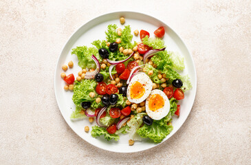 Soft-boiled egg Easter fresh vegetable salad with tomatoes, chickpea, olives, onion and green lettuce. Healthy food,  breakfast. Top view - 748946418