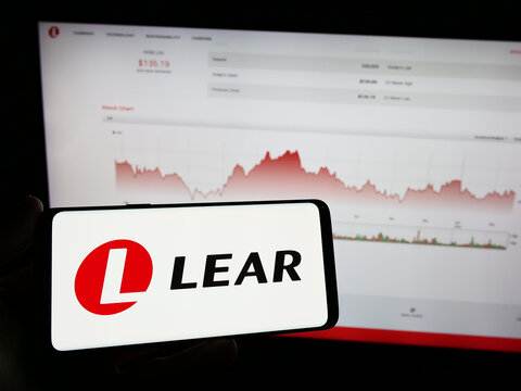 Stuttgart, Germany - 02-22-2024: Person holding mobile phone with logo of American automotive supply company Lear Corporation in front of web page. Focus on phone display.