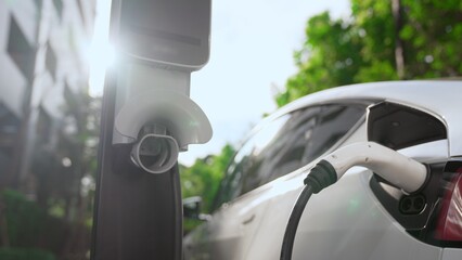 EV electric car charging in green sustainable city outdoor garden in summer. Urban sustainability...