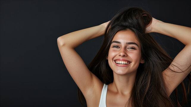 Close-up of an attractive girl with toothy smile staning at isolated dark background. Copy space. Studio shot.