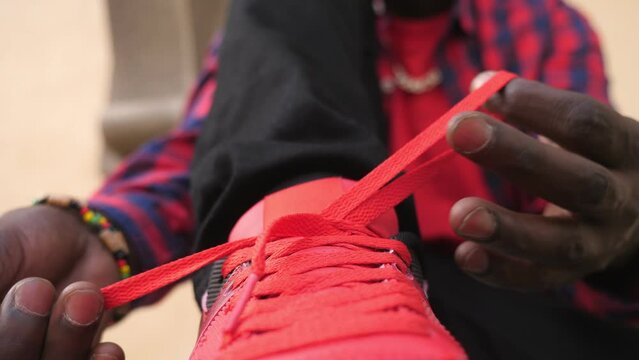 close up on hands of young african man tying a knot on his sneakers