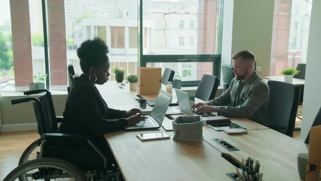 Businesswoman in wheelchair and her partner working at office