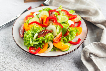 vegetable salad of fresh tomatoes, cucumbers, onions, lettuce on white plate.