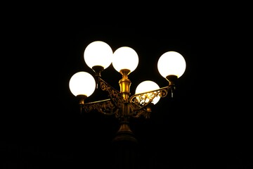 Unikatowa lampa świeci w nocy. Staromodna lampa na mieści świeci wieczorną porą