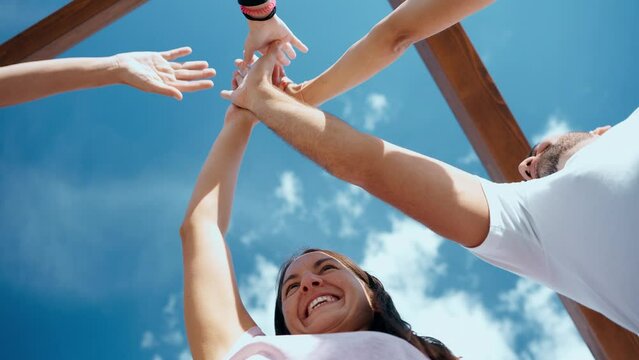 Smiling people high fiving against blue sky