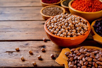 beans, lentils and spices in a wooden bowl on wood table