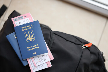 Two ukrainian biometrical passports with air flight tickets on black touristic backpack close up
