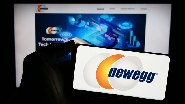 Stuttgart, Germany - 02-24-2024: Person holding mobile phone with logo of American computer retail company Newegg Commerce Inc. in front of web page. Focus on phone display.