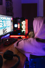 Unrecognizable graphic designer with sweatshirt hood on working in his room