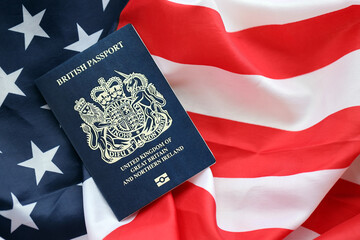 Fototapeta premium Blue British passport on United States national flag background close up. Tourism and diplomacy concept