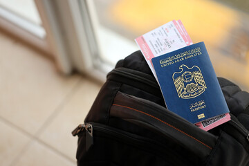 Blue United Arab Emirates passport with airline tickets on touristic backpack close up. Tourism and...