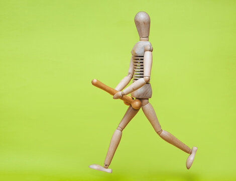 The wooden man is holding a stick in his hands that resembles a large erotic penis and is running after someone. Concept of large size, priapism and strong libido. Sexual maniac.