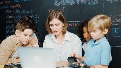 Caucasian teacher using laptop and explain about engineering system while diverse student holding...