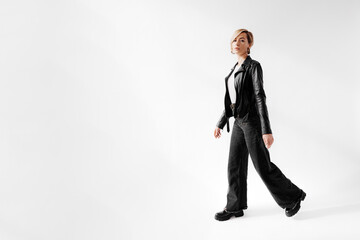 A young woman strides forward in a timeless black leather jacket and flared jeans, exuding a cool...