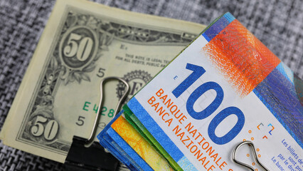 Half-folded Swiss franc and US dollar banknotes