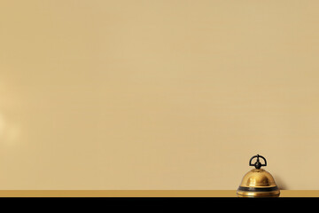 sonnette dorée et noire de la réception d'un hôtel de luxe sur le comptoir pour appeler le personnel. Fond beige avec espace négatif pour texte copyspace Hostellerie, voyages, réservation vacances  - obrazy, fototapety, plakaty
