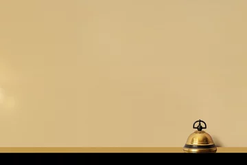 Fototapeten sonnette dorée et noire de la réception d'un hôtel de luxe sur le comptoir pour appeler le personnel. Fond beige avec espace négatif pour texte copyspace Hostellerie, voyages, réservation vacances  © Noble Nature