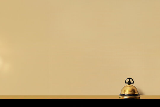 sonnette dor&eacute;e et noire de la r&eacute;ception d'un h&ocirc;tel de luxe sur le comptoir pour appeler le personnel. Fond beige avec espace n&eacute;gatif pour texte copyspace Hostellerie, voyages, r&eacute;servation vacances 