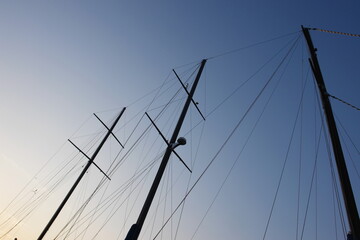 A sailboat with three masts is silhouetted against a blue sky