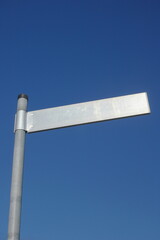 A street sign is standing on a pole in front of a blue sky - 748989090