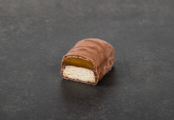 Small cookie with caramel in chocolate glaze. In the section. Dark gray background. Close-up