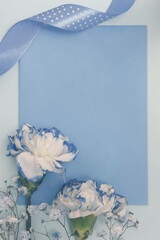 Niebieska kartka papieru w otoczeniu niebiesko-białych goździków. - obrazy, fototapety, plakaty