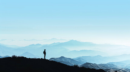 A silhouette of a person standing on a hill facing a vast landscape. - obrazy, fototapety, plakaty