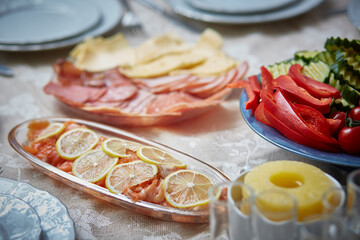 Fototapeta na wymiar Slices of red fish with lemon are presented on the festive table. Lemon perfectly complements the savory red fish. Enjoy the delicious combination of red fish and Lemon.