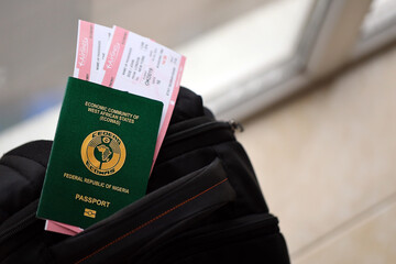 Green Nigerian passport with airline tickets on touristic backpack close up. Tourism and travel...