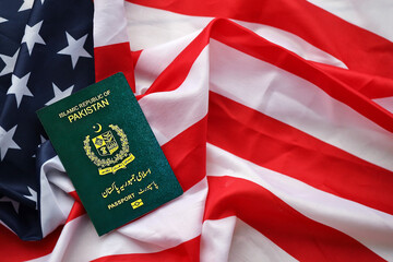 Green Islamic Republic of Pakistan passport on United States national flag background close up....