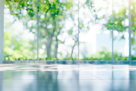 Blurred empty modern open space office with large windows and green trees on the outside, environment friendly business background