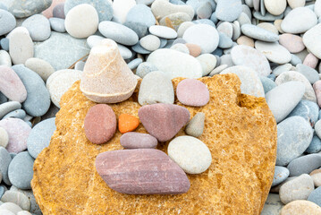 Fototapeta na wymiar Assorted Stones on Large Yellow Rock Surrounded by Pebbles