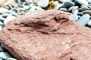 Textured Red Rock Formation Amongst Smooth Pebbles