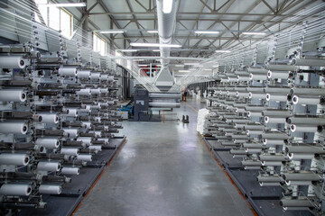 Factory equipment in perspective. Rows with coils of polypropylene threads for weaving cloth. Automatic machine. Nobody.