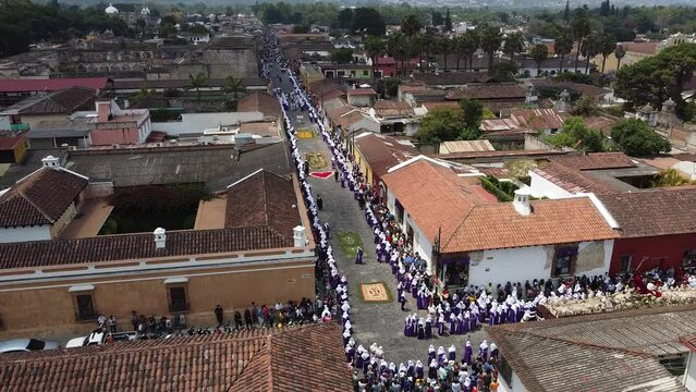 Antigua, Guatemala, Lent procession walks over dyed sawdust carpet in colonial town & UNESCO World Heritage Site with most famous Holy Week celebrations . Semana Santa Drone shot, aerial view