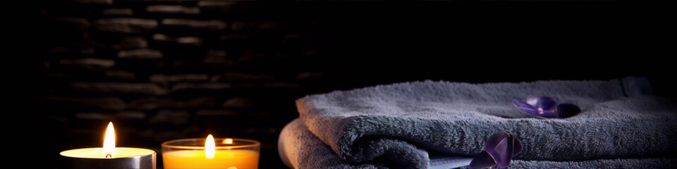 Bath towels and aromatic candles on dark background, spa concept