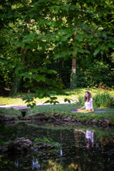 Beautiful woman with gorgeous curly hair doing yoga in nature, dressed in white and yellow combination, concept: active healthy life