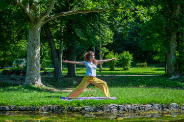 Beautiful woman with gorgeous curly hair doing yoga in nature, dressed in white and yellow combination, concept: active healthy life