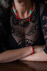 Woman in black lace dress with beautiful coral red and turquoise necklace. Coral necklace on a woman nude neck with a turquoise and old triangle pendant. Concept: gift, celebrating, affection, love