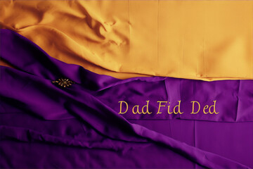 Purple and gold fabric with a gold brooch and the words "Dad Fid Ded" written in gold letters.