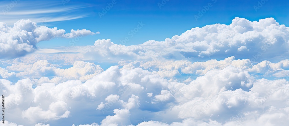 Poster Above the earth, the plane soars through the skies, offering a clear view of the fluffy, white clouds drifting amidst the vast blue expanse.