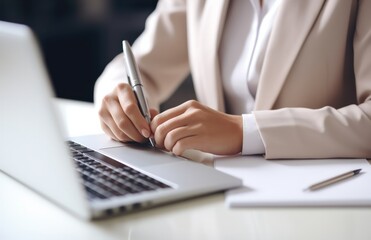 a young woman writing notes by a desk with laptop