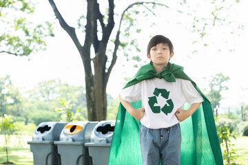 Cheerful young superhero boy with cape and recycle symbol promoting waste recycle, reduce, and...