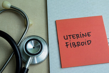 Concept of Uterine Fibroid write on sticky notes with stethoscope isolated on Wooden Table.