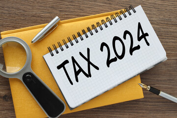 Tax 2024 yellow notepad with text on the page. white pen